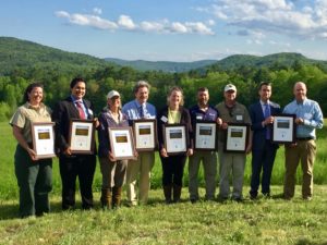 A group stands with honorary plaques during the June 2017Hudson Farm conservation celebration