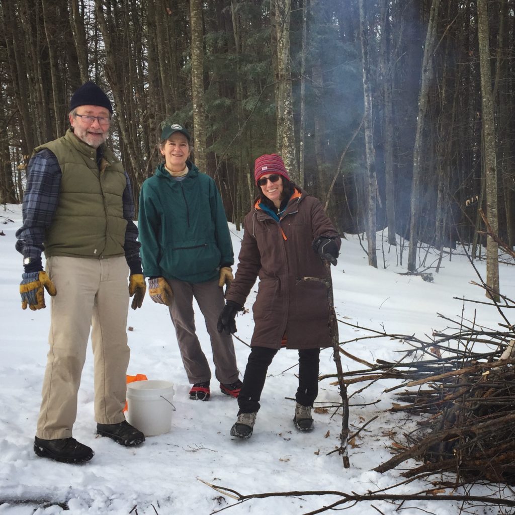 Volunteers tend a fire to remove cut brush on the summit of Balch Hill in winter. 